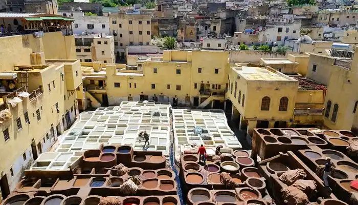 View of Chouara Tannery in Fes, Morocco, showcasing vibrant stone vats filled with natural dyes and artisans at work in the heart of the medina