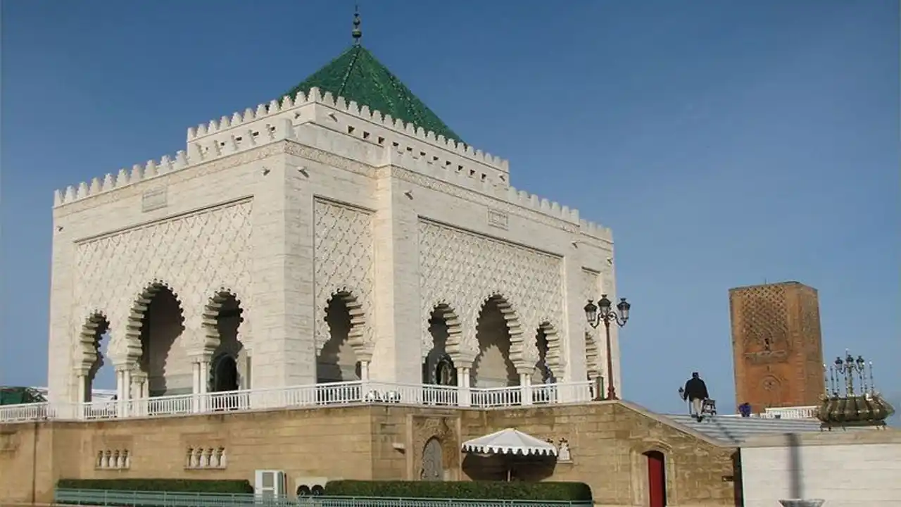 Exterior view of the Mausoleum of Mohammed V in Rabat, showcasing its iconic green tiled roof and intricate Moroccan architecture.