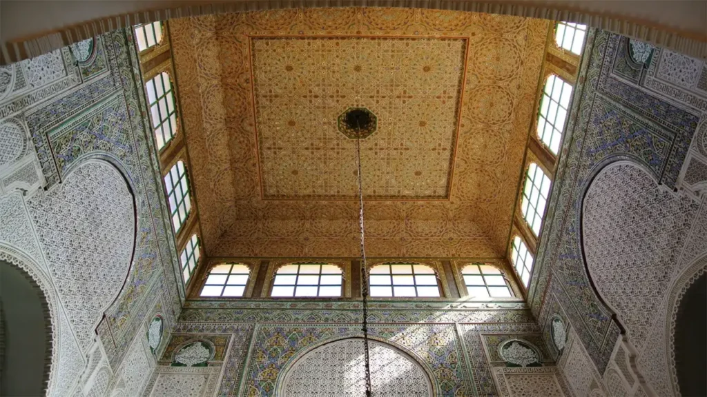 Intricate architecture of the Mausoleum of Moulay Ismail in Meknes, featuring zellij tilework, marble columns, and ornate cedar wood carvings.