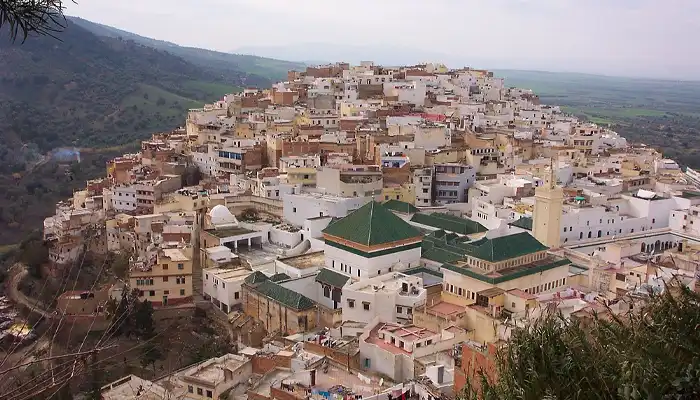 Scenic view of Moulay Idriss Zerhoun, a sacred hilltop town near Meknes, Morocco, with whitewashed buildings and breathtaking countryside surroundings.