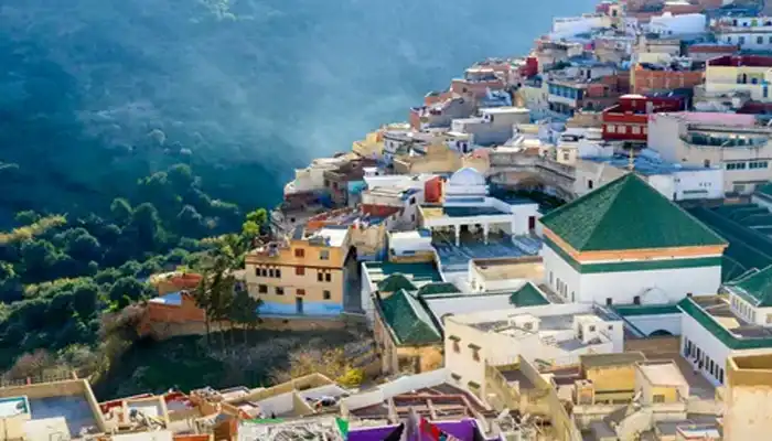 Panoramic view of the sacred town of Moulay Idriss, with its iconic cylindrical minaret and hillside homes in Morocco.