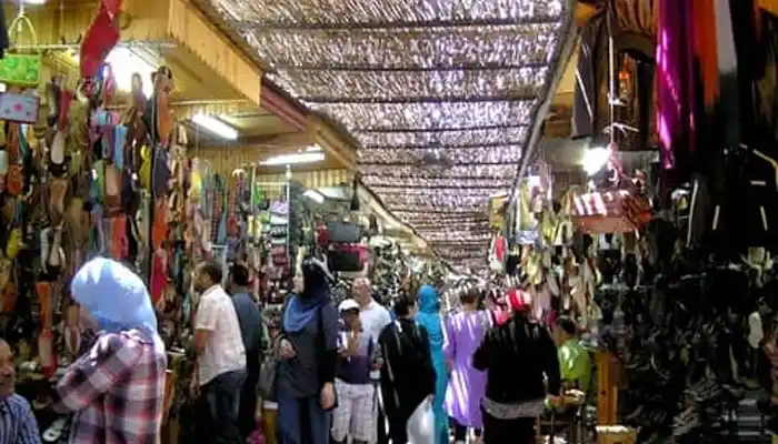 A vibrant view of Souk Sebbat in Meknes, featuring colorful textiles, traditional Moroccan footwear, and bustling stalls, reflecting the souk’s lively atmosphere and craftsmanship.