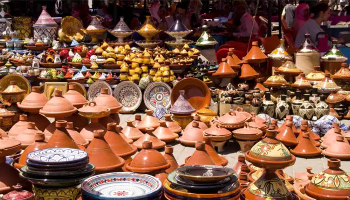 Colorful display of traditional crafts in Meknes, Morocco, featuring handmade pottery, intricate textiles, and vibrant artisan goods in a bustling market setting.